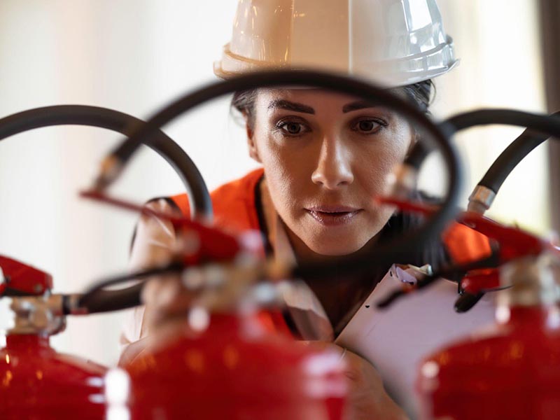 A professional safety inspector inspects fire extinguishers - close up.